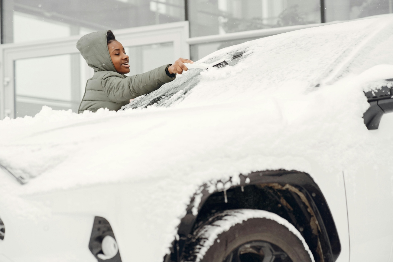 woman cleaning snow off her car